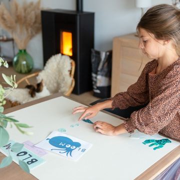 Petite fille réalisant des collages à côté du poêle à granulés Aäsgard