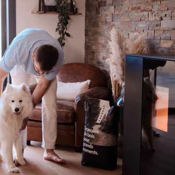 Thomas Lavault et son chien Timo à côté du poêle à granulés Aäsgard