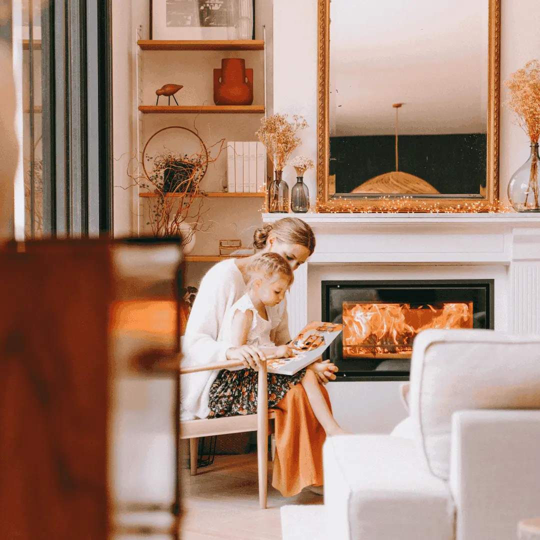 mère et fille lisant un livre devant un poêle