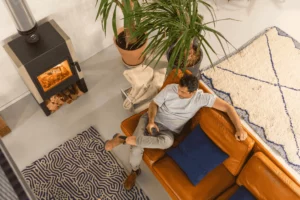poêle dans un salon avec un homme sur un canapé