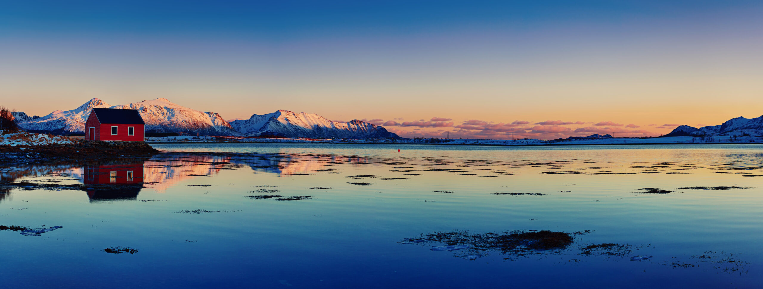 Nos marques paysage avec beau lac d hiver maison de rorbu rouge et montagnes enneigees au coucher du soleil sur les iles lofoten dans le nord de la norvege vue panoramique scaled